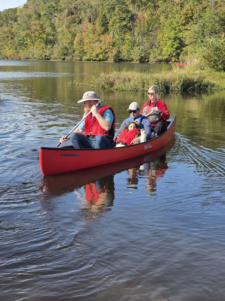 2 people sitting in the middle of a canoe while 2 others paddle the canoe
