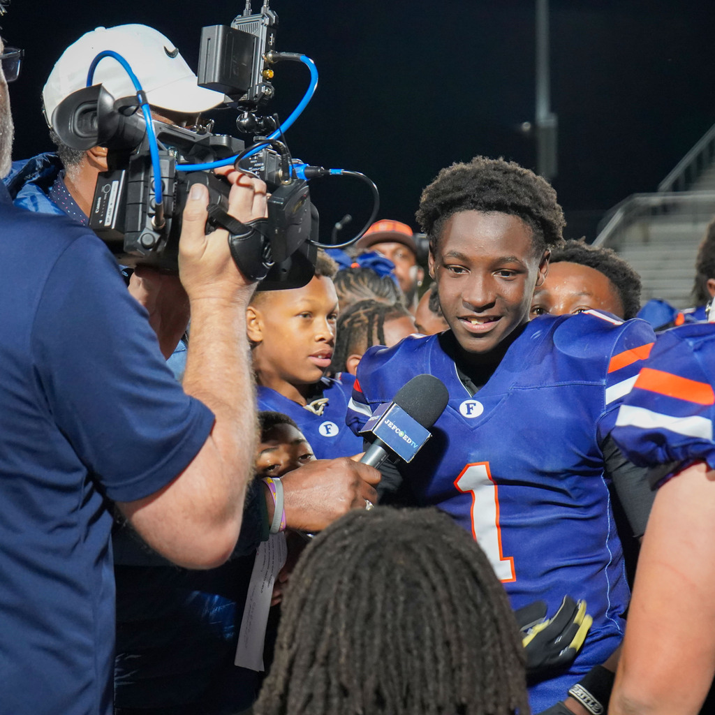 A football player does an interview with a reporter after a football game.
