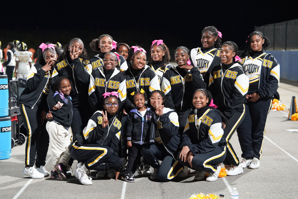 McAdory Middle School cheerleaders pose for a photo with two children during a football game.