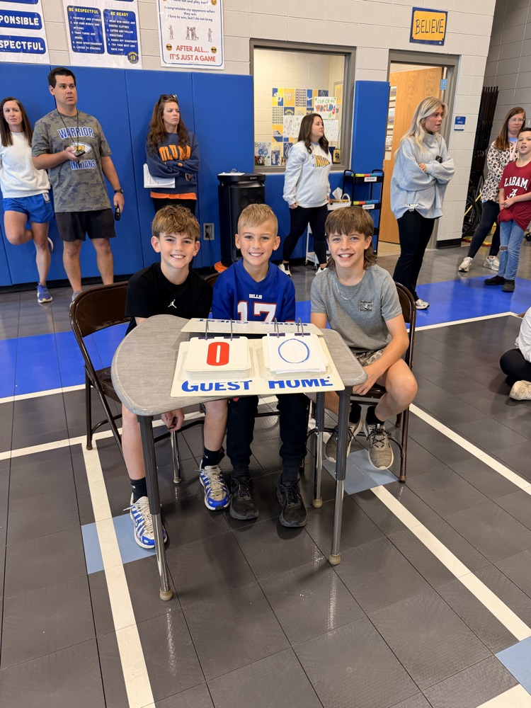 three boys sitting behind a table keeping score for the newcomb game 