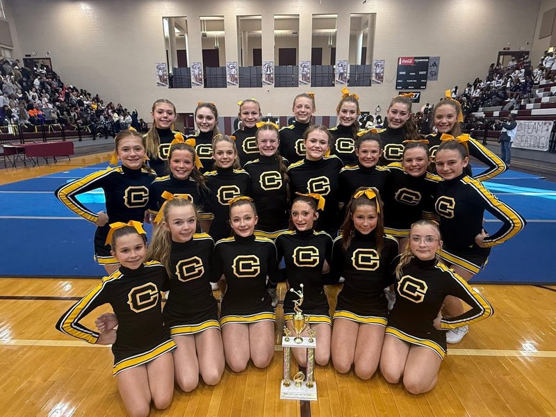 Corner Middle School cheerleaders sit and stand in Gardendale High School's gym and pose with a trophy.