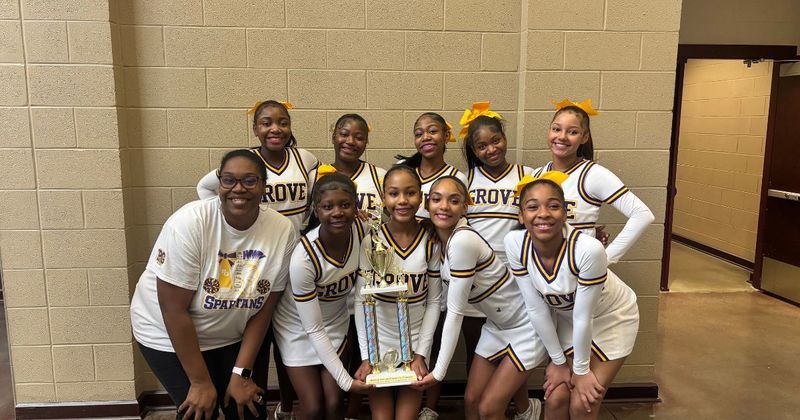 Pleasant Grove Middle School cheerleaders smile and pose with a trophy.