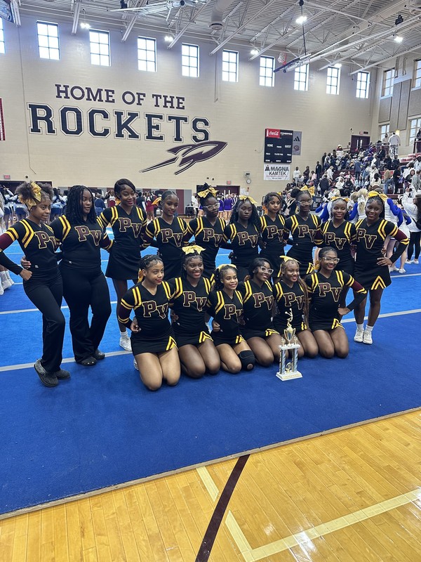 Pinson Valley High School cheerleaders pose with a trophy inside a school gym.