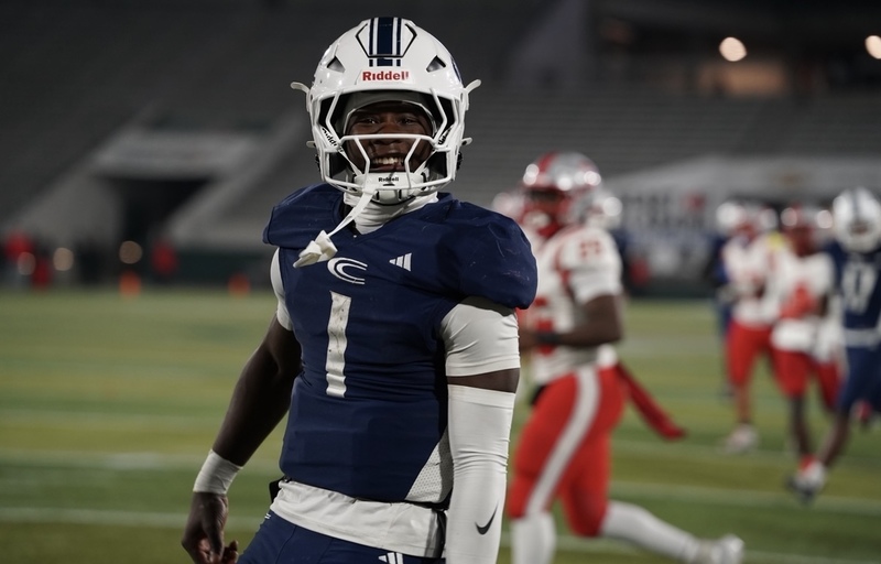 CCHS Quarterback Aaron Frye smiles at the camera while standing on a football field.