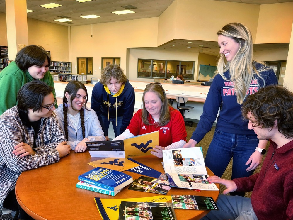 School counselors at Washington high School review college catalogs with students around a table in the library