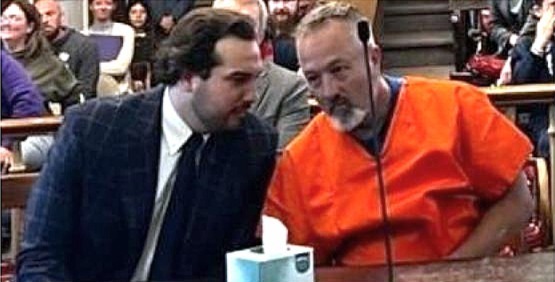 lawyer sits at defendant table with Mr. Daly, who is wearing an orange jumpsuit