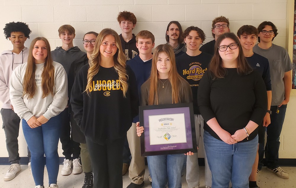 Members of the NTHS at WHS pose in a group against a wall holding their award