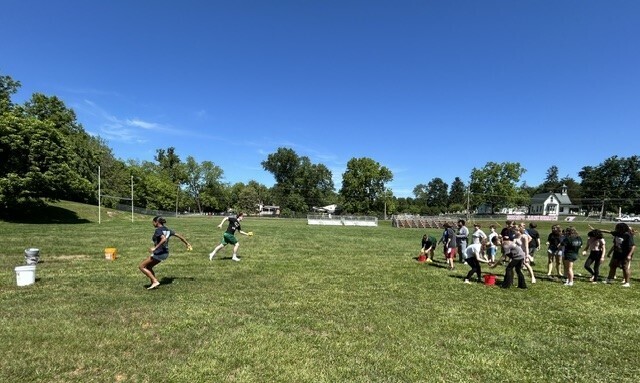 Students in a relay race to fill buckets with water using sponges