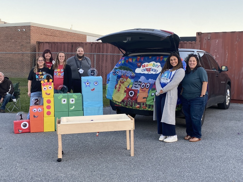 Group of people in front of car decorated with "Numbers Block" characters