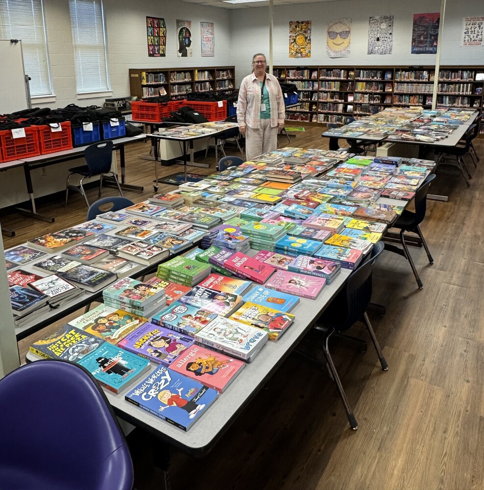 Librarian standing with tables of books