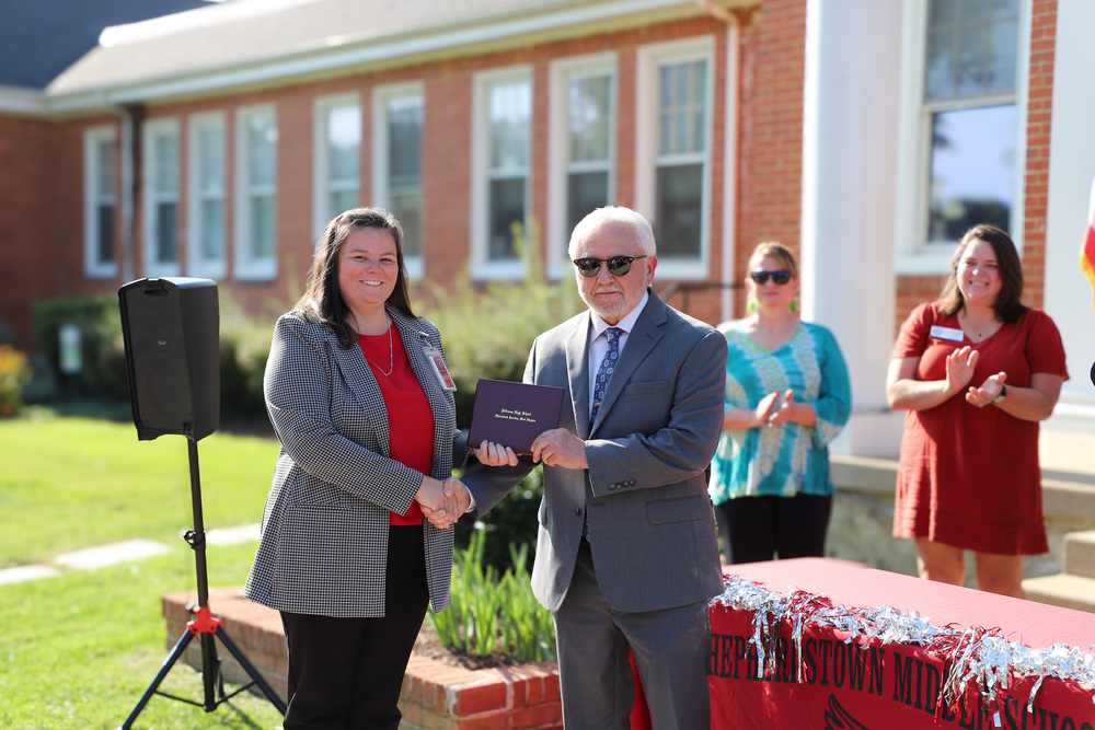 Ms. Horn handing Mr.Bartley a diploma while shaking his hand