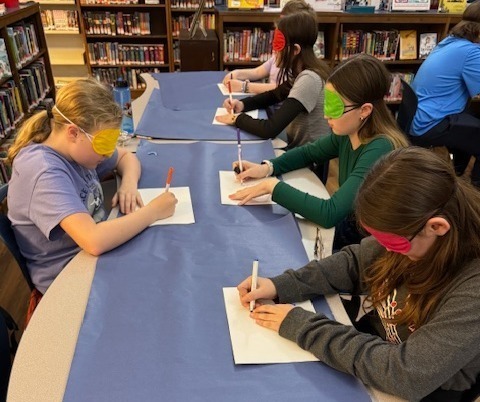Students drawing a holiday picture with blindfolds on.