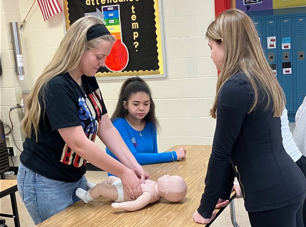 Students performing CPR on a baby