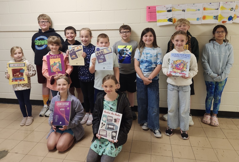 SJE students show off the new instruction materials their Friends of Music grant helped purchase