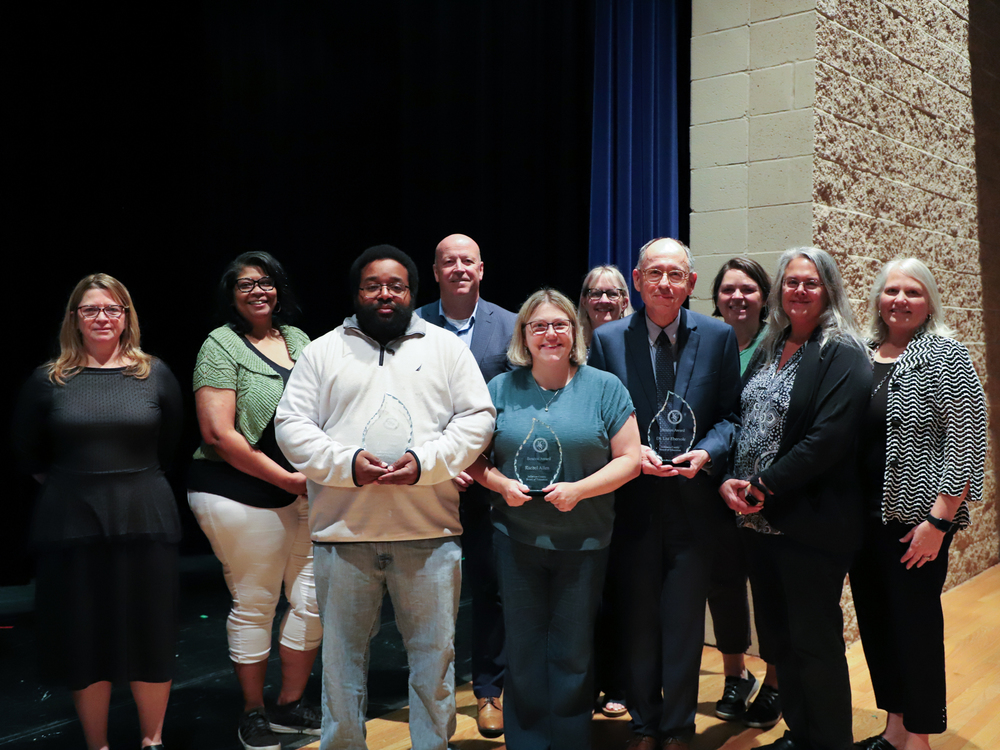 Members of the Jefferson County BOE stand with the inaugural Beacon Award winners on a stage at the May 27 BOE meeting
