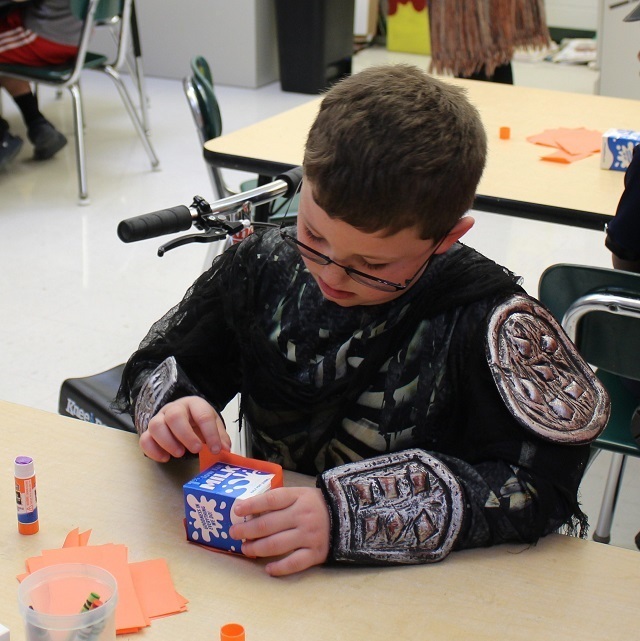 A student dressed as a knight working on a craft.
