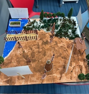 A diorama showing sand, water, and trees