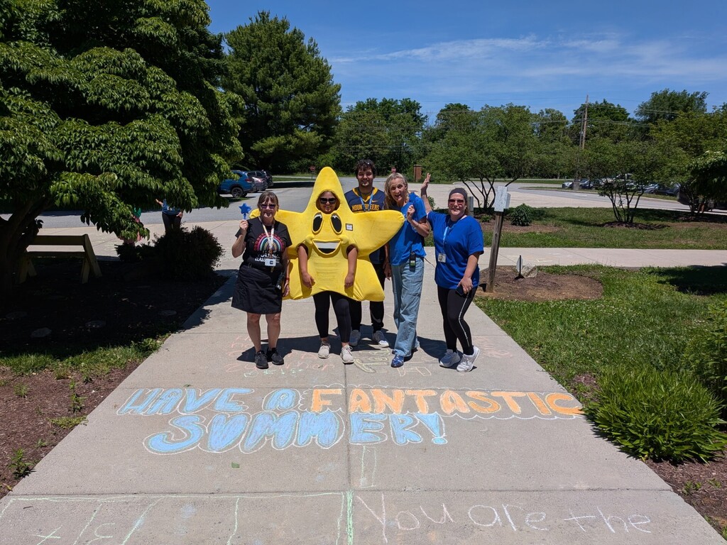 Staff standing in front of a chalk message that says have a fantastic summer.