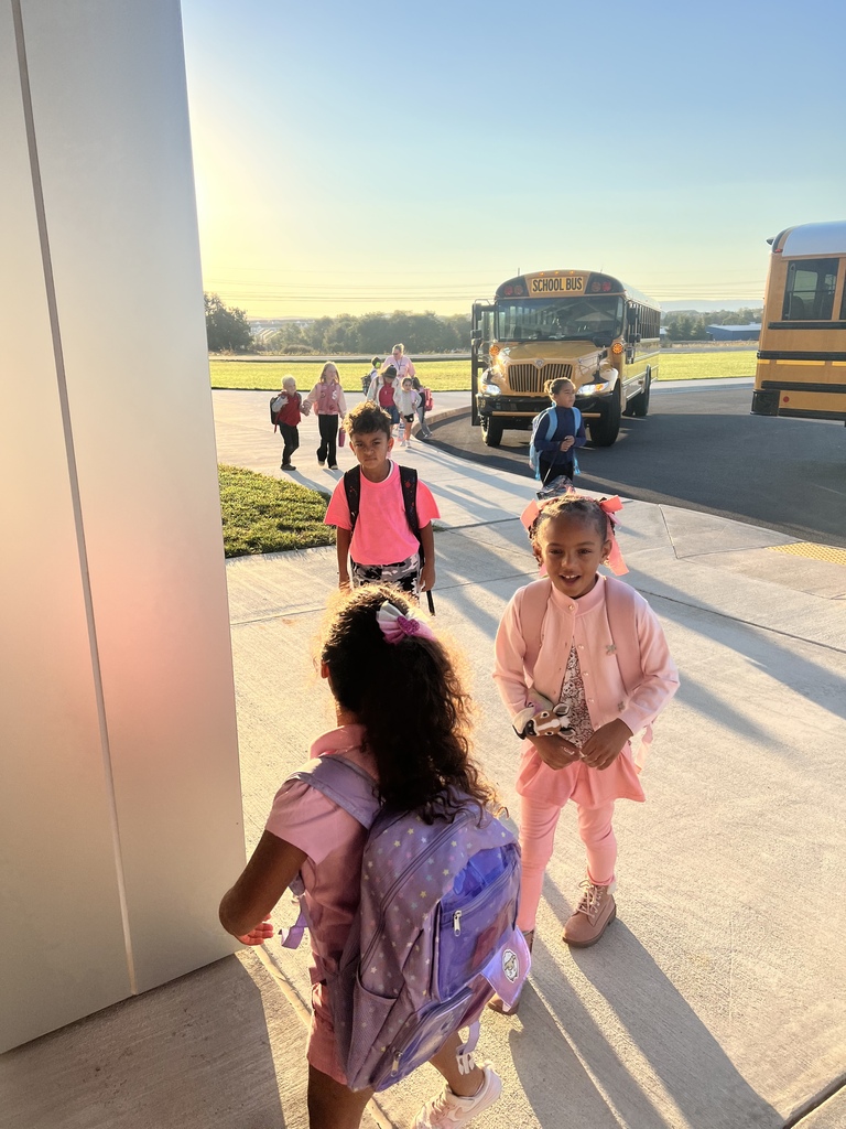 Students walking off the bus with pink clothing.