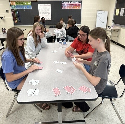 Students and teacher playing a card game