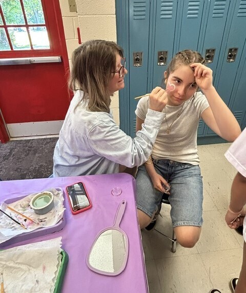 Teacher painting a student's face