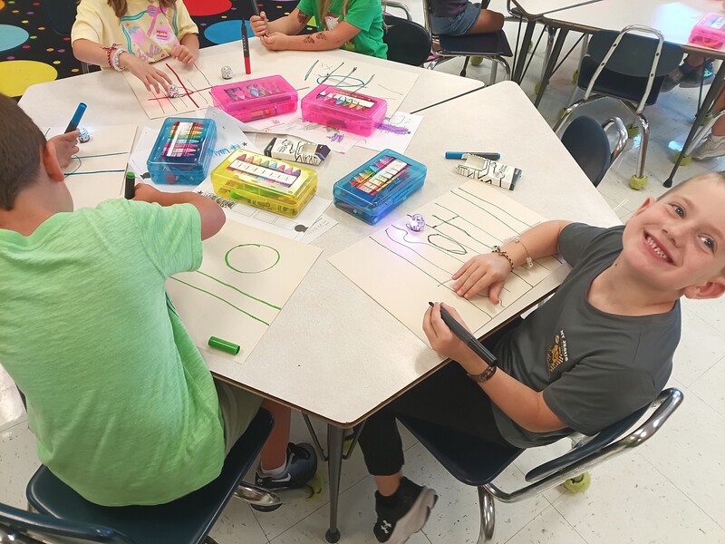 students using Ozobots to practice lines and circles