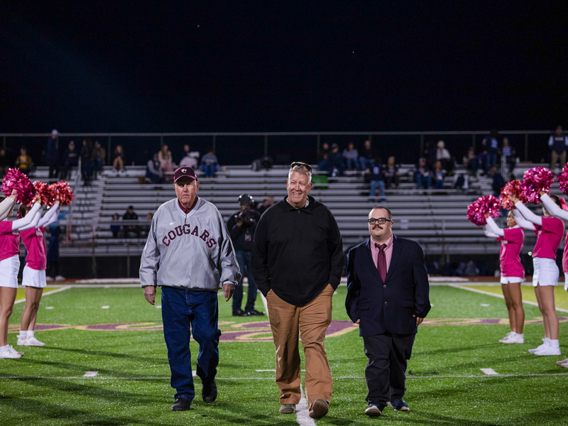 John Lowery, Jr. walking into Cougar Stadium between a row of cheerleaders with his escorts, including his father