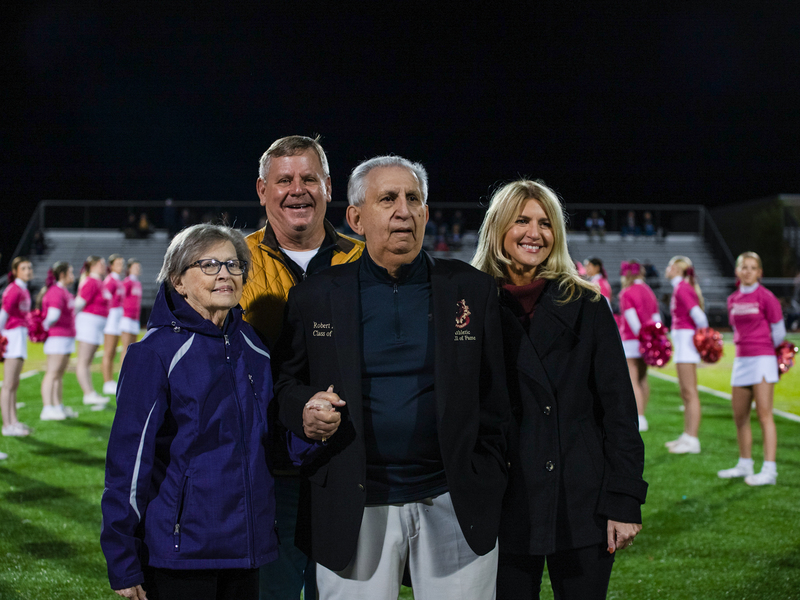 Bob Rizzo with his wife and family in Cougar Stadium with cheeerleaders in the background