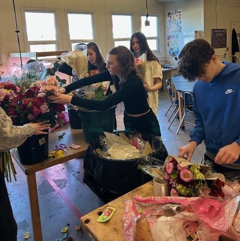 Students making flower arrangements in coffee mugs