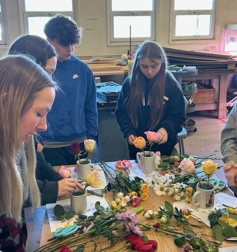 Students making flower arrangements in coffee mugs