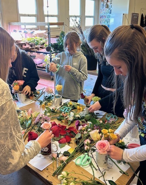 Students making flower arrangements in coffee mugs