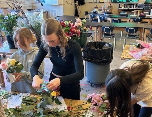 Students making flower arrangements in coffee mugs