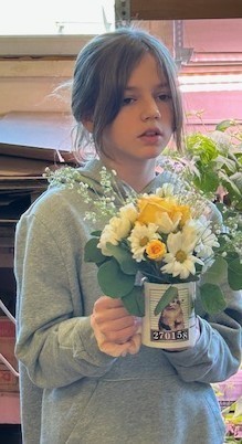 Student with coffee mug flower arrangement