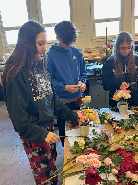 Students making flower arrangements in coffee mugs