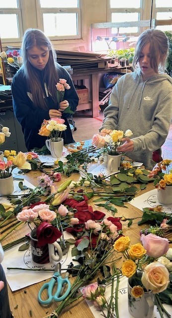 Students making flower arrangements in coffee mugs