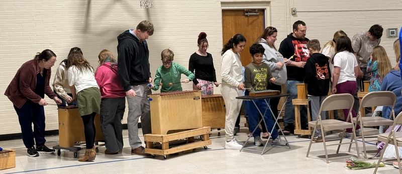 3rd graders teaching adults how to play the xylophones