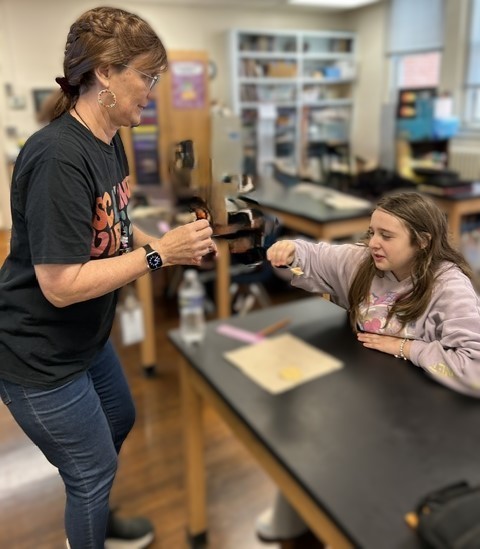 Teacher giving a student a taste of maple syrup