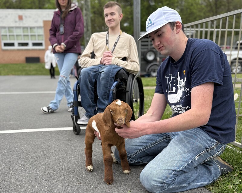 high school students showing off the baby goat