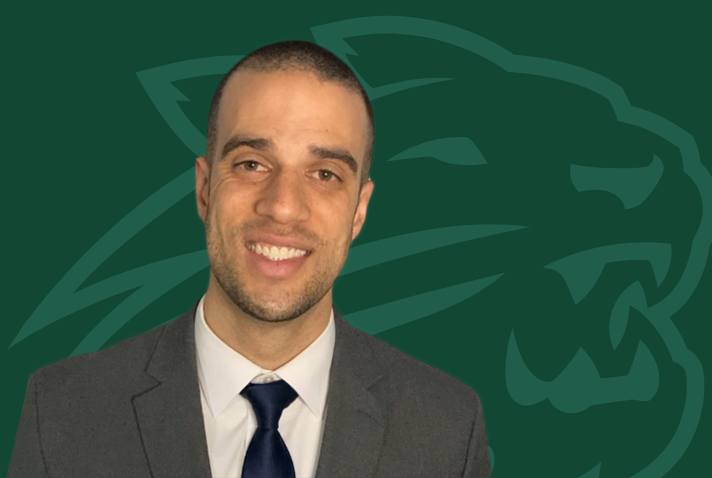 portrait of Daniel russel with wildcat head graphic behind him