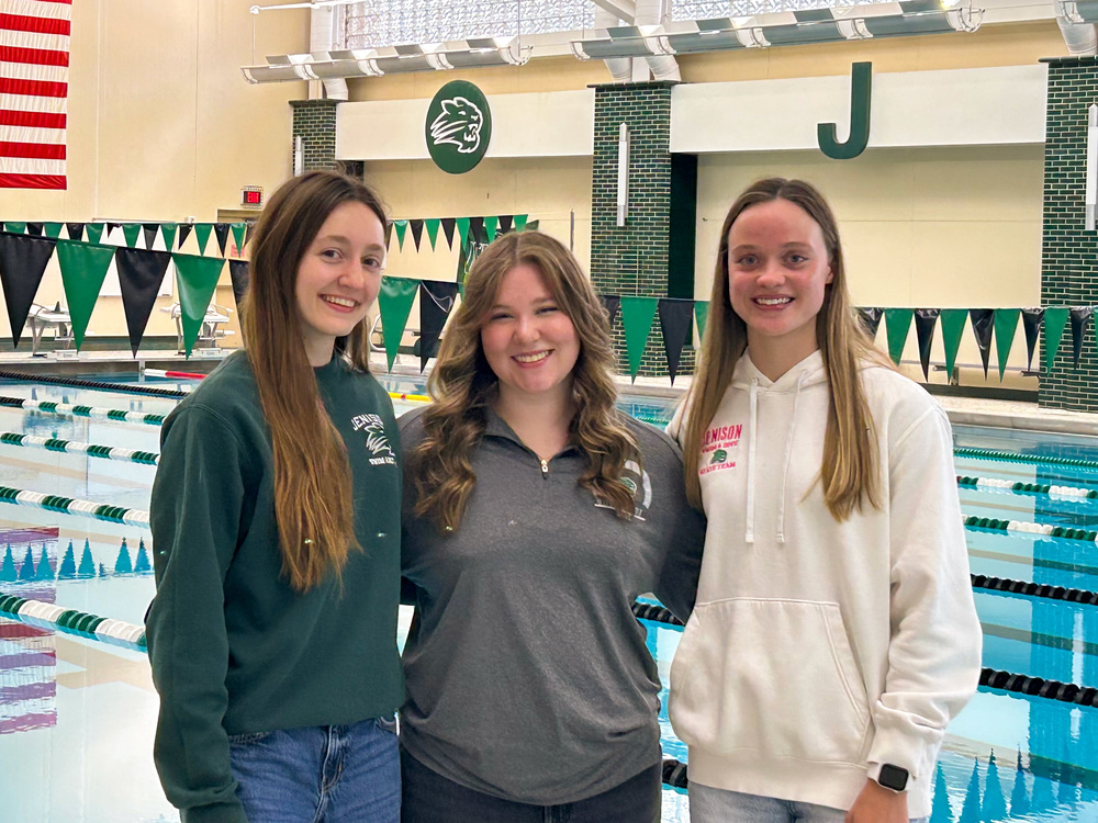 Girls swimmers posing in front of pool
