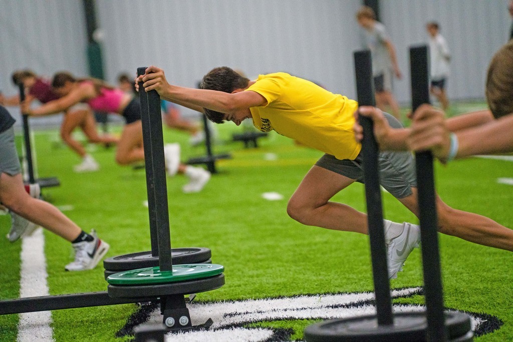 Student pushing weights on a field