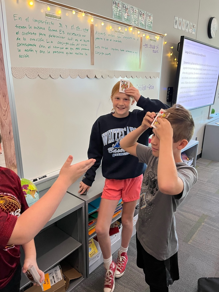 Students holding playing cards to their foreheads.