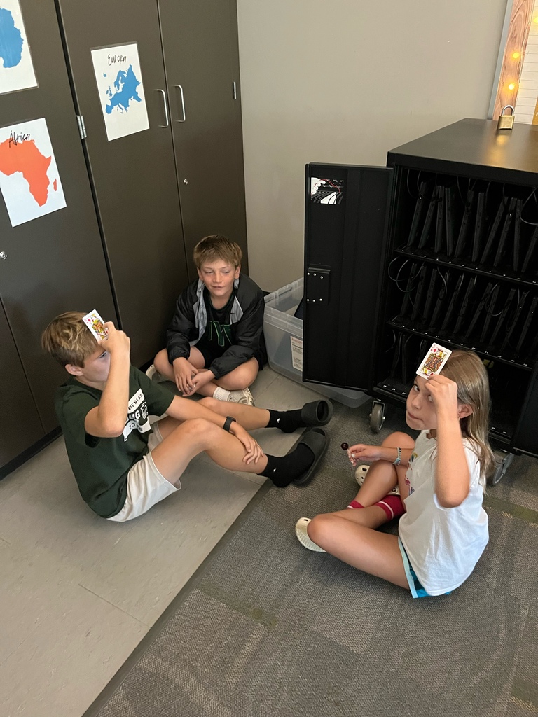 Students holding playing cards to their foreheads.