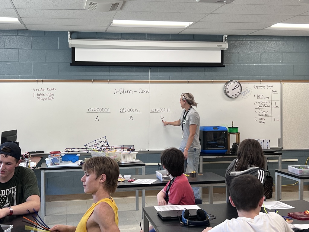J-Stem Students sitting at tables creating binary code bracelets