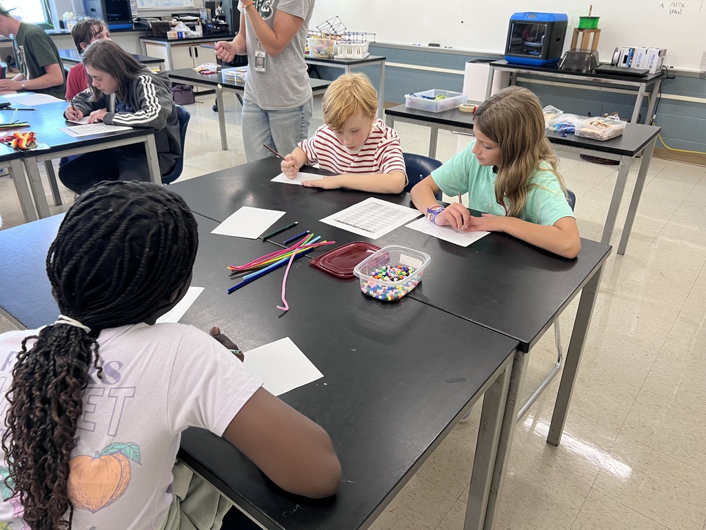 J-Stem Students sitting at tables creating binary code bracelets