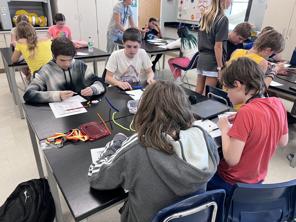 J-Stem Students sitting at tables creating binary code bracelets