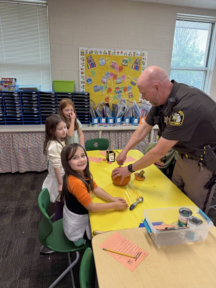 SRO carving pumpkin with students