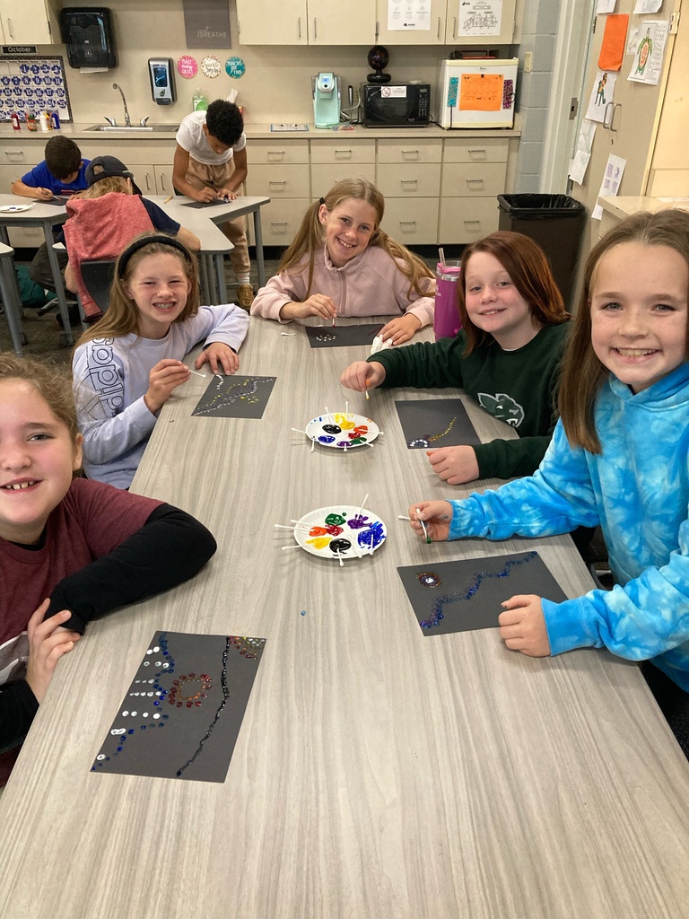 5 students sitting around a table doing aboriginal dot art
