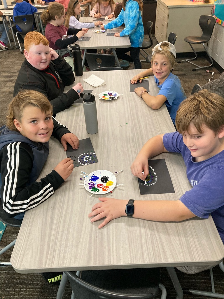 4 students sitting around a table doing aboriginal dot art