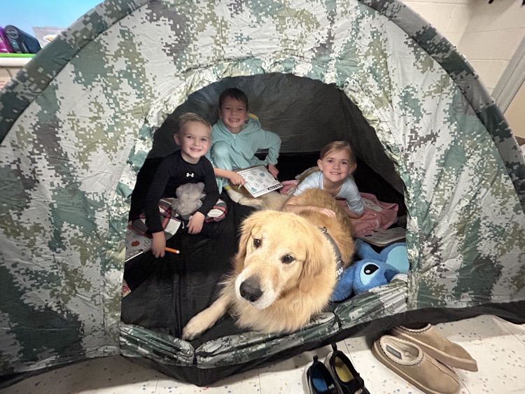 students reading in a tent with a dog